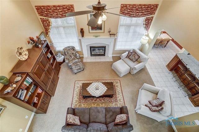 tiled living room with a tile fireplace, a healthy amount of sunlight, and ceiling fan