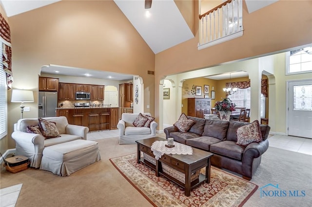 living room featuring light colored carpet, a towering ceiling, and a notable chandelier