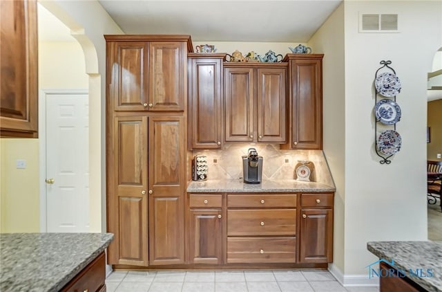 kitchen featuring light stone countertops, light tile patterned floors, and decorative backsplash