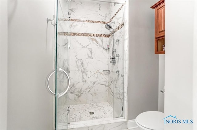 bathroom featuring a shower with door and toilet