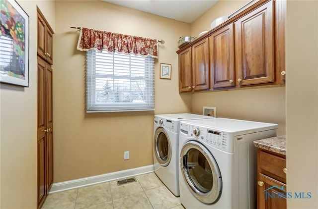 washroom with cabinets, light tile patterned floors, and washing machine and clothes dryer