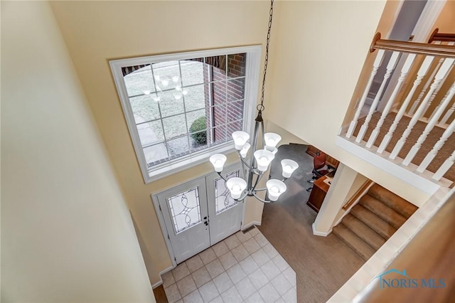 tiled entryway featuring an inviting chandelier and french doors