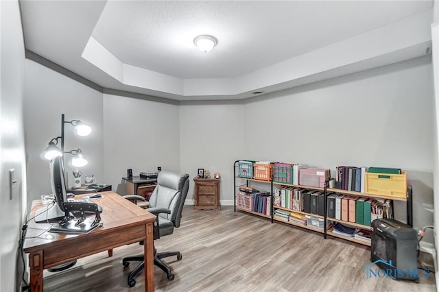 office featuring hardwood / wood-style flooring and a raised ceiling