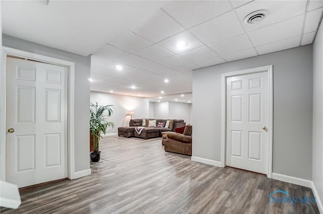 living room featuring wood-type flooring and a paneled ceiling