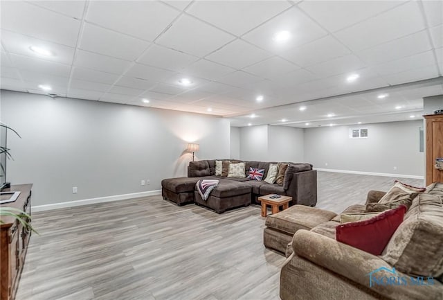 living room with a paneled ceiling and light hardwood / wood-style floors