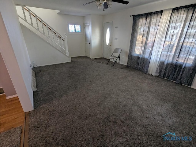 interior space featuring dark carpet and ceiling fan