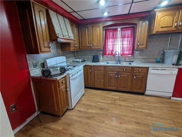 kitchen with premium range hood, white appliances, sink, and light wood-type flooring