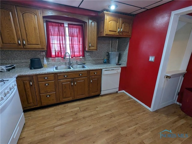 kitchen featuring tasteful backsplash, white appliances, light hardwood / wood-style floors, and sink