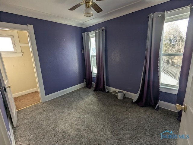 carpeted spare room featuring plenty of natural light and ceiling fan