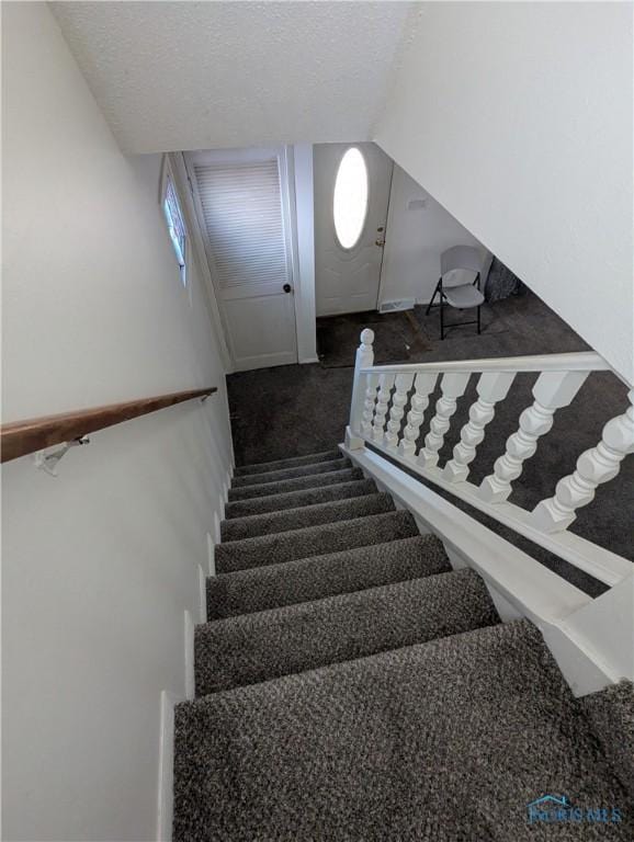 stairs featuring vaulted ceiling, carpet floors, and a textured ceiling