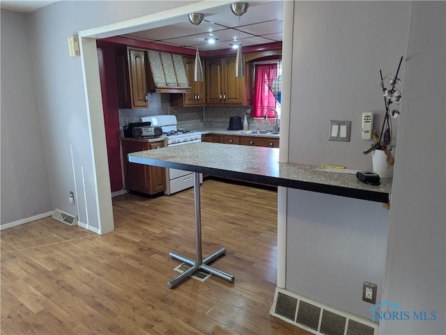 kitchen with premium range hood, tasteful backsplash, sink, white gas range oven, and light wood-type flooring