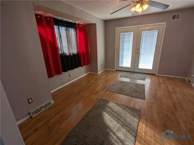 doorway with french doors, hardwood / wood-style floors, a textured ceiling, and a wealth of natural light