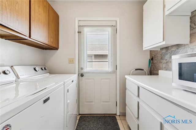 washroom featuring cabinets, independent washer and dryer, and light tile patterned flooring