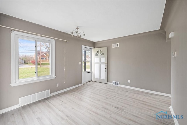 spare room featuring an inviting chandelier and light wood-type flooring