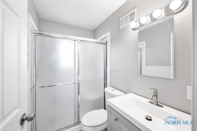 bathroom featuring vanity, toilet, and a shower with door