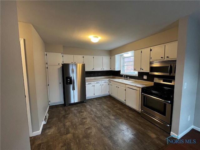 kitchen with white cabinetry, appliances with stainless steel finishes, dark hardwood / wood-style floors, and sink