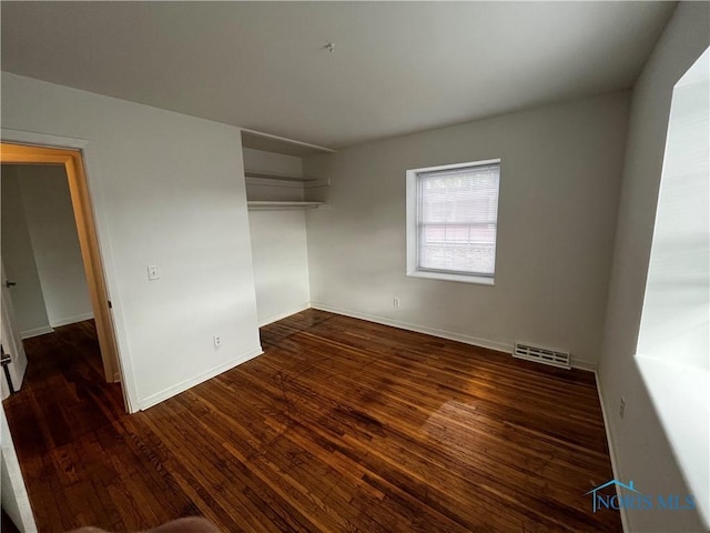 unfurnished bedroom featuring dark wood-type flooring and a closet