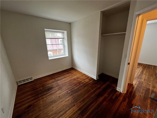 unfurnished bedroom featuring dark wood-type flooring and a closet