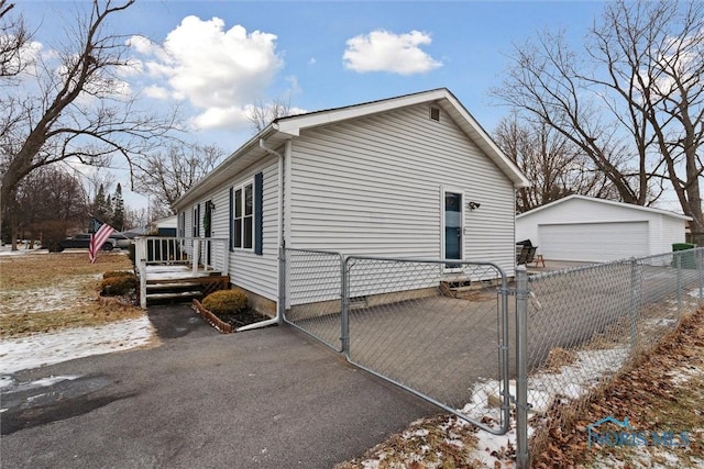 view of snowy exterior featuring an outbuilding and a garage