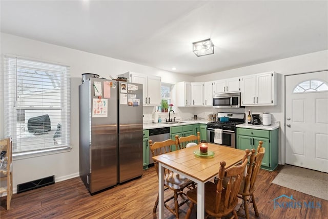 kitchen featuring sink, hardwood / wood-style flooring, appliances with stainless steel finishes, white cabinetry, and green cabinetry