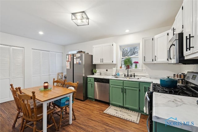 kitchen with appliances with stainless steel finishes, hardwood / wood-style floors, white cabinetry, sink, and green cabinets