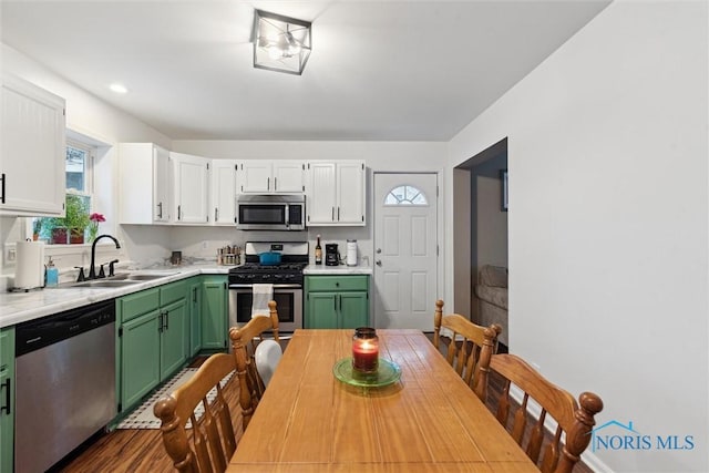 kitchen with sink, green cabinetry, hardwood / wood-style flooring, stainless steel appliances, and white cabinets