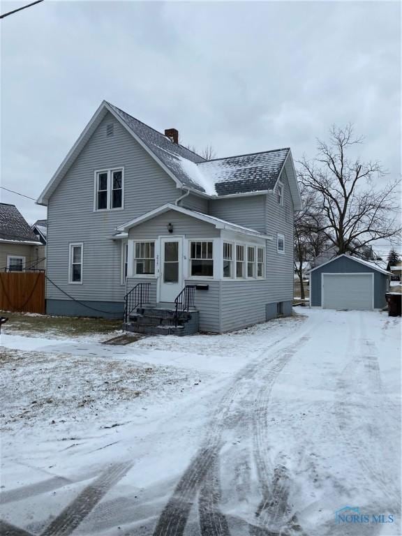 snow covered property with an outbuilding and a garage