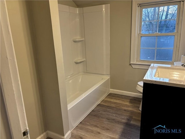 full bathroom with hardwood / wood-style flooring, vanity, shower / tub combination, and toilet