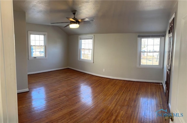 empty room featuring ceiling fan, lofted ceiling, dark hardwood / wood-style floors, and a wealth of natural light