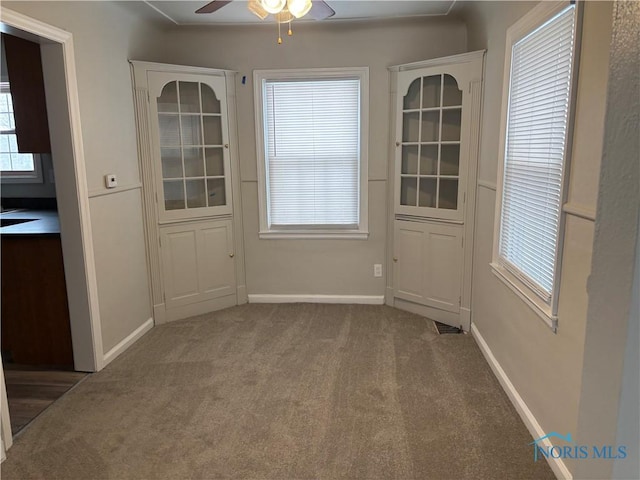 unfurnished dining area with ceiling fan and carpet