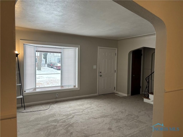 interior space featuring light colored carpet and a textured ceiling