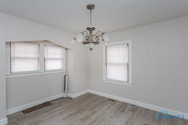 unfurnished room with an inviting chandelier and light wood-type flooring