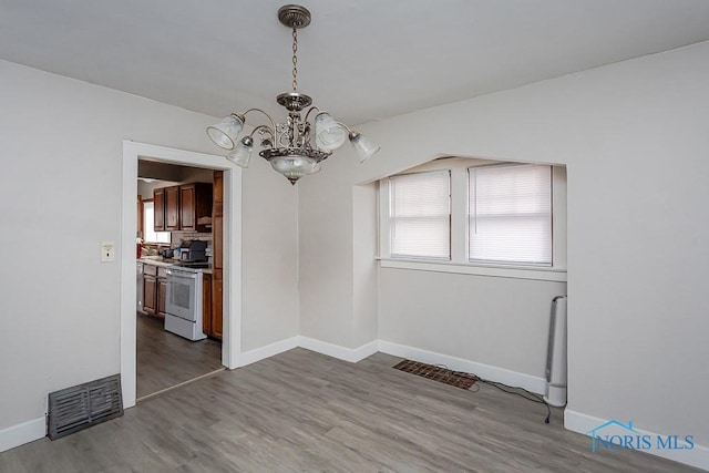 unfurnished dining area featuring a notable chandelier, light hardwood / wood-style flooring, and a healthy amount of sunlight