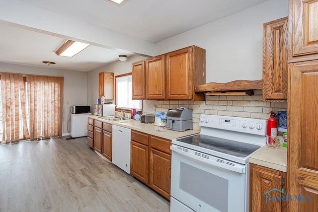 kitchen featuring sink, backsplash, white appliances, and light hardwood / wood-style floors