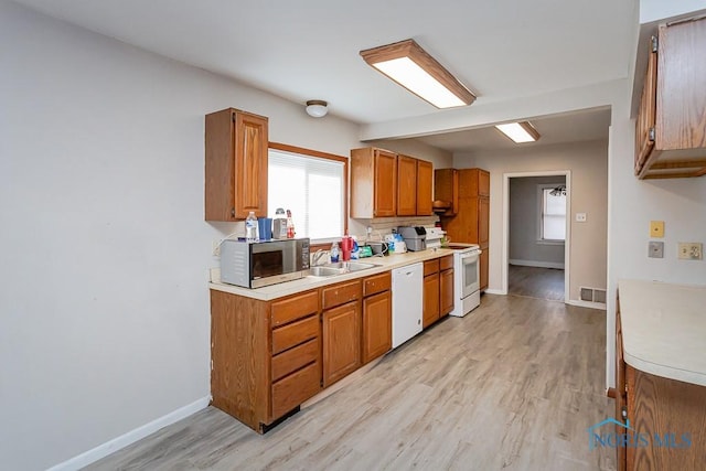 kitchen with white appliances, sink, and light hardwood / wood-style floors