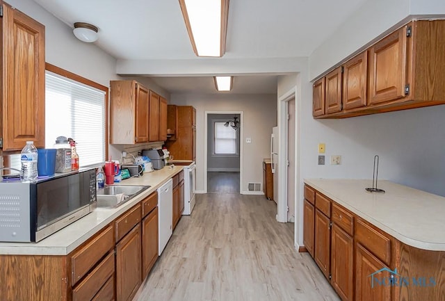 kitchen with range, white dishwasher, sink, and light hardwood / wood-style flooring