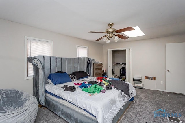 carpeted bedroom with ceiling fan, a skylight, and a closet