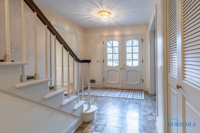 foyer with french doors and a textured ceiling