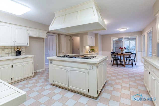 kitchen featuring custom exhaust hood, stainless steel gas cooktop, tile counters, and white cabinets