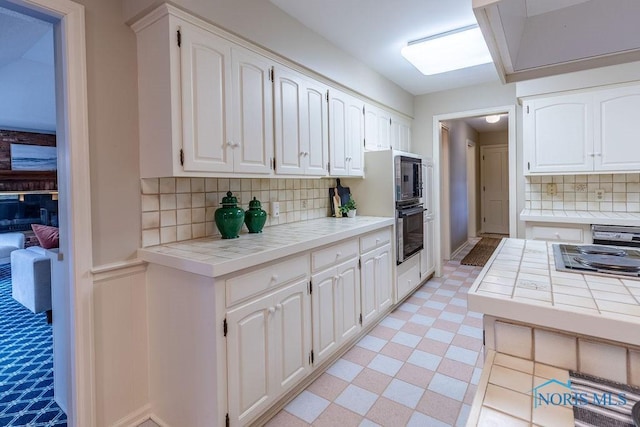 kitchen with tile counters, oven, and white cabinets