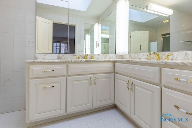 bathroom with tile walls, vanity, a skylight, and tile patterned floors