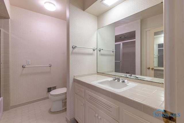 bathroom with toilet, vanity, and walk in shower