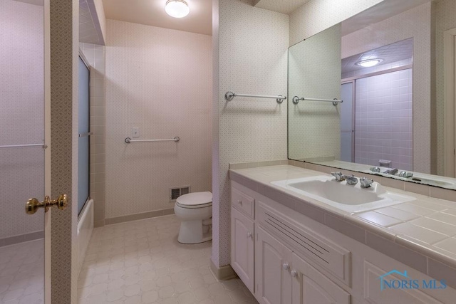 full bathroom featuring vanity, combined bath / shower with glass door, and toilet