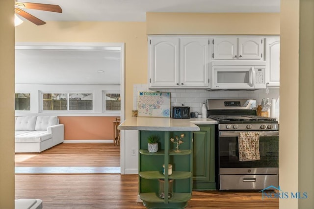 kitchen with hardwood / wood-style flooring, ceiling fan, white cabinets, decorative backsplash, and stainless steel range with gas cooktop