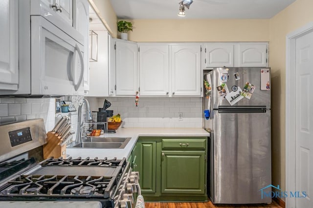 kitchen with stainless steel appliances, sink, white cabinets, and backsplash