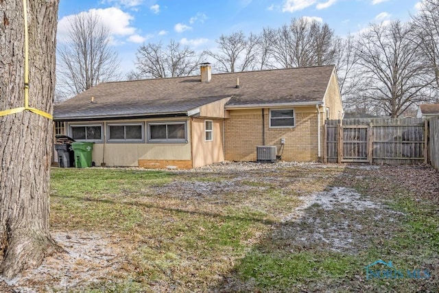 back of property with central AC unit and a lawn