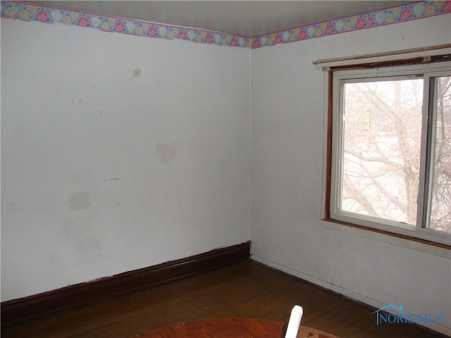 spare room featuring plenty of natural light and dark hardwood / wood-style flooring