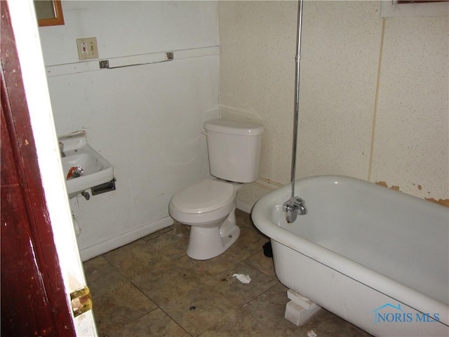 bathroom featuring toilet and a tub to relax in