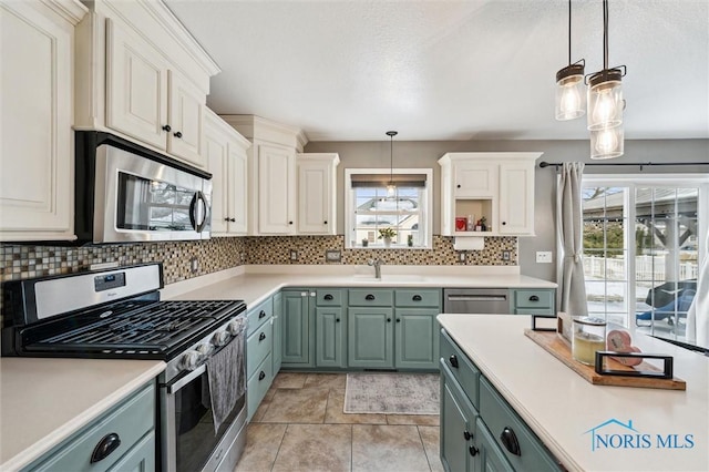 kitchen with stainless steel appliances, white cabinetry, pendant lighting, and decorative backsplash