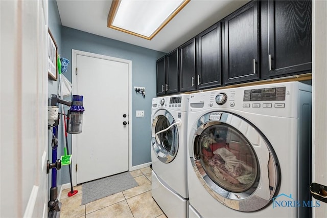 laundry room with cabinets, light tile patterned floors, and washing machine and clothes dryer